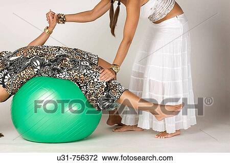 Stock Image - Girls in their early 40s playing with an exercise ball. Fotosearch
