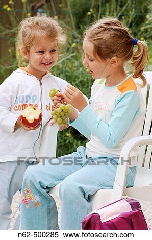 Stock Photography - Girls laughing and eating fruits. Fotosearch