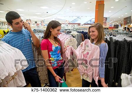 Girls shop while boy talks on cell phone View Large Photo Image Stock Image - Girls shop while boy talks on cell phone. Fotosearch