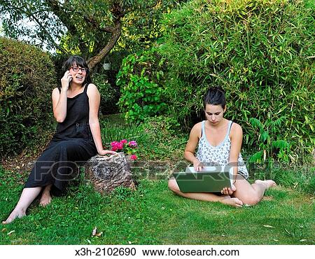 girls using a laptop computer and a cellphone sitting in a garden, Ile de France region, France, Europe. View Large Photo Image Stock Image - girls using a laptop computer and a cellphone sitting in a garden, Ile de France region, France, Europe.. Fotosearch