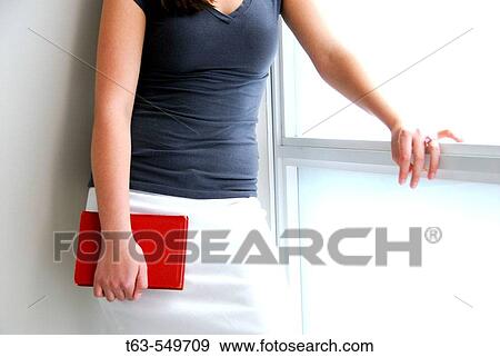 girl/woman 20 yrs old holding red book by window View Large Photo Image Stock Photo - girl/woman 20 yrs old holding red book by window. Fotosearch