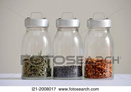 Stock Photo - Glass jars with spices. From left to right: rosemary, poppy seed, chilli. Gray background.. Fotosearch