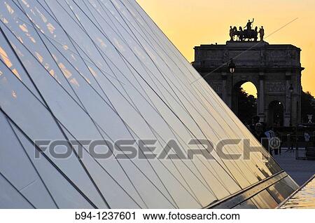 Stock Image - Glass pyramid, by Ieo Ming Pei, at Napol? on court. Palais du Louvre. Mus? e du Louvre and Arc de Triomphe du Carrousel. Paris, France.. Fotosearch