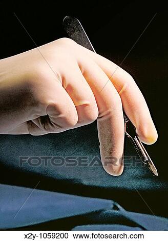 Gloved hand of a surgeon holding a scalpel View Large Photo Image Stock Image - Gloved hand of a surgeon holding a scalpel. Fotosearch