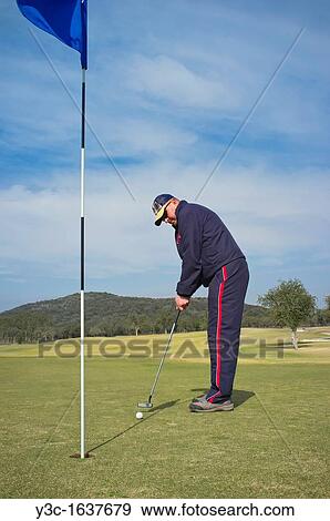 Golf player using putter for putting the ball into the hole View Large Photo Image Stock Photo - Golf player using putter for putting the ball into the hole. Fotosearch