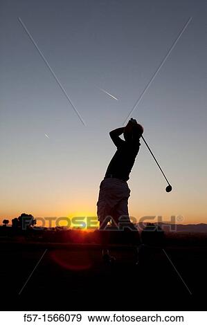 Stock Photo - Golfer driving the ball at sunset. Fotosearch