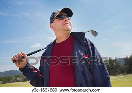 Stock Image - Golfer with golf iron watching his ball in flight. Fotosearch