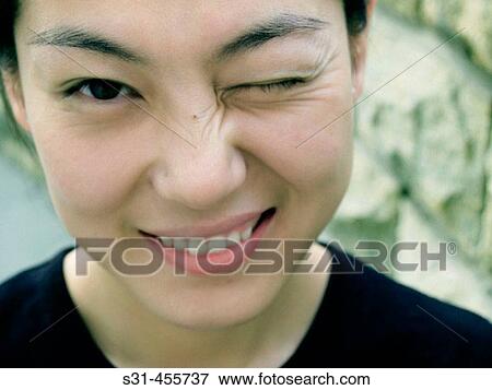 Stock Photo - Good looking chinese female winking one eye and smiling. Fotosearch