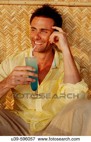 Good-looking man in a yellow shirt drinking a blue cocktail and laughing, shot in India. View Large Photo Image Stock Photo - Good-looking man in a yellow shirt drinking a blue cocktail and laughing, shot in India.. Fotosearch
