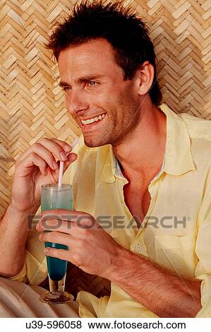 Good-looking man in a yellow shirt drinking a blue cocktail and laughing, shot in India. View Large Photo Image Stock Photo - Good-looking man in a yellow shirt drinking a blue cocktail and laughing, shot in India.. Fotosearch