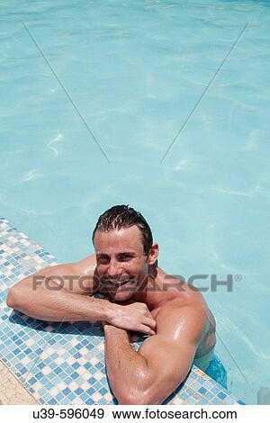 Good-looking man leaning against the side of a swimming pool in India, and smiling at camera. View Large Photo Image Stock Photo - Good-looking man leaning against the side of a swimming pool in India, and smiling at camera.. Fotosearch