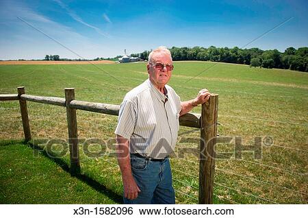 Grain producer standing by fence of farm with grain elevator in background Montgomery County Maryland USA View Large Photo Image Stock Photograph - Grain producer standing by fence of farm with grain elevator in background Montgomery County Maryland USA. Fotosearch