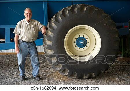 Grain producer standing by tire of a tractor used for harvesting, Montgomery County Maryland USA View Large Photo Image Picture - Grain producer standing by tire of a tractor used for harvesting, Montgomery County Maryland USA. Fotosearch