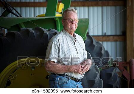 Stock Photography - Grain producer standing by tire of a tractor used for harvesting, Montgomery County Maryland USA. Fotosearch