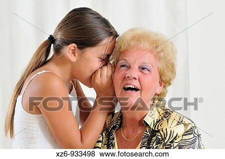 Granddaughter wispering in grandmothers ear View Large Photo Image Stock Photo - Granddaughter wispering in grandmothers ear. Fotosearch