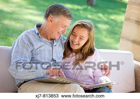 Grandfather and granddaughter looking at photo album View Large Photo Image Stock Image - Grandfather and granddaughter looking at photo album. Fotosearch