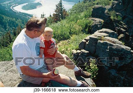 Grandfather and grandson on a hike enjoying the view and a brief rest View Large Photo Image Stock Photo - Grandfather and grandson on a hike enjoying the view and a brief rest. Fotosearch