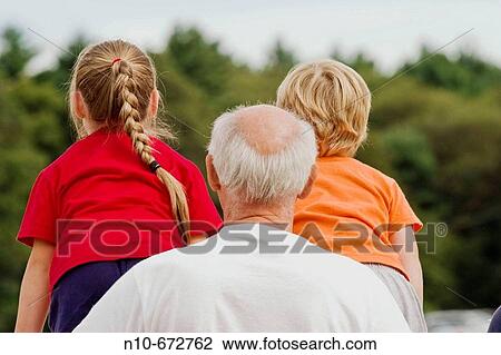 Grandfather holding onto his blond granddaughter and grandson who are standing on a fence. View Large Photo Image Stock Image - Grandfather holding onto his blond granddaughter and grandson who are standing on a fence.. Fotosearch