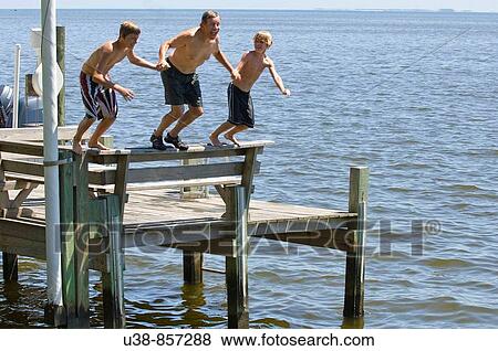 Grandfather jumping from dock with grandsons View Large Photo Image Stock Photo - Grandfather jumping from dock with grandsons. Fotosearch