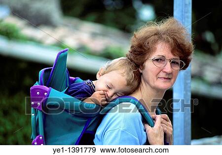 Grandmother carrying her sleeping grandson in a backpack View Large Photo Image Stock Photo - Grandmother carrying her sleeping grandson in a backpack. Fotosearch