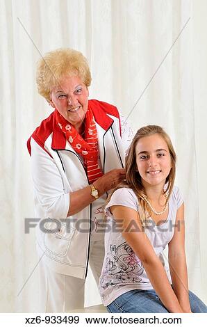 Grandmother helps her granddaughter to wear a pearl necklace View Large Photo Image Stock Photo - Grandmother helps her granddaughter to wear a pearl necklace. Fotosearch