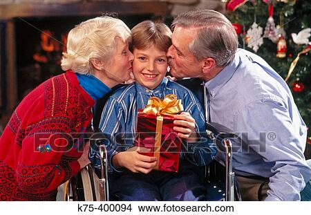 Picture - Grandparents kissing grandson at Christmas. Fotosearch