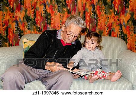 Great Grandad reads a book to his great grandchild on a coach. View Large Photo Image Stock Photograph - Great Grandad reads a book to his great grandchild on a coach.. Fotosearch
