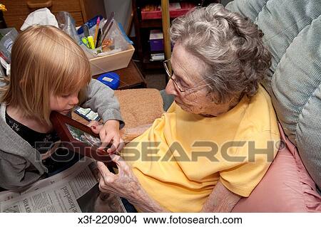 Great granddaughter showing great grandma family photo age 3 and 96. Battle Lake Minnesota MN USA. View Large Photo Image Picture - Great granddaughter showing great grandma family photo age 3 and 96. Battle Lake Minnesota MN USA.. Fotosearch