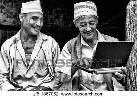 Stock Image - Great image of modern technology with local Hindu men and new laptop computer in village of Bhaktapur a town near Kathmandu Nepal. Fotosearch