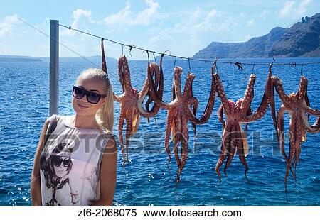 Greece Santorini Oia Cyclades Greek Islands fishing village with Europen woman tourist below Oia with octapus squid hanging on rope Greek; Islands; beautiful; peaceful; beauty; Greek 5. View Large Photo Image Stock Photography - Greece Santorini Oia Cyclades Greek Islands fishing village with Europen woman tourist below Oia with octapus squid hanging on rope Greek; Islands; beautiful; peaceful; beauty; Greek 5.. Fotosearch