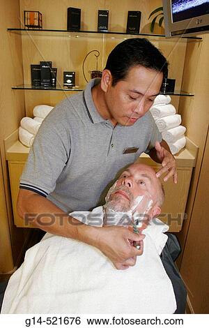 Stock Photograph - Greenhouse Salon, Asian male shaves White man, cream. MS Noordam. Holland America Line. Puerto Rico, Atlantic Ocean. Fotosearch