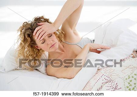 Stock Photo - Groggy young woman in bed. Fotosearch