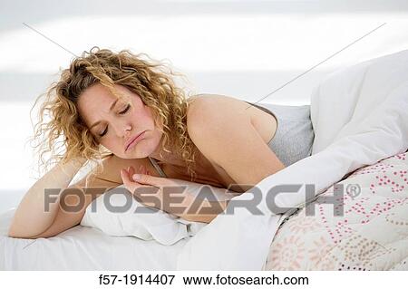Stock Photo - Groggy young woman in bed. Fotosearch