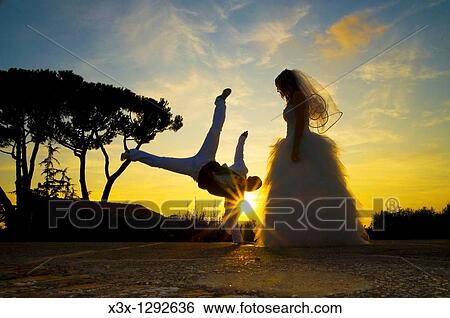 Stock Photograph - Groom celebrating marriage with a Capoeira stance at sunset. Fotosearch