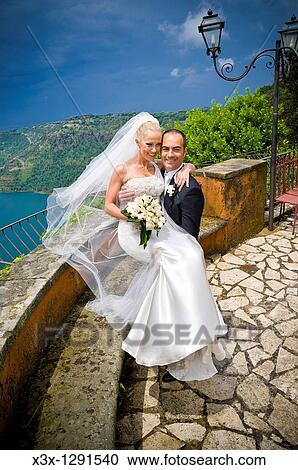 Stock Image - Groom holding bride in front of a Lake. Fotosearch