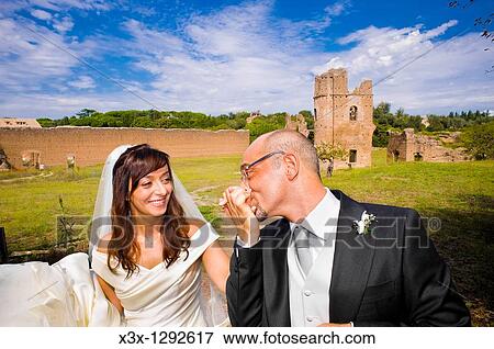 Groom kissing bride hand among ancient remains of Villa di Massenzio in Rome Italy View Large Photo Image Stock Photo - Groom kissing bride hand among ancient remains of Villa di Massenzio in Rome Italy. Fotosearch