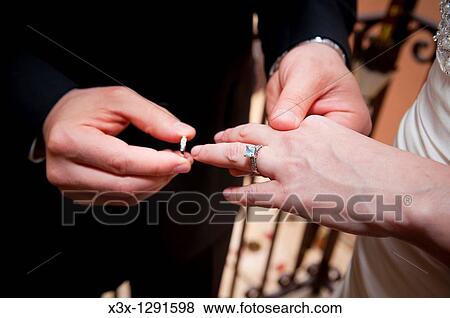 Stock Photo - Groom putting the wedding on the bride. Fotosearch