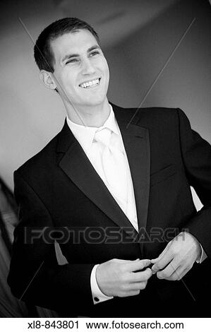 Stock Image - groom smiling, buttoning up suit. Fotosearch