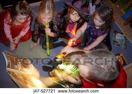 Stock Image - Group of children at a Halloween party, dressed up, holding torches. Fotosearch