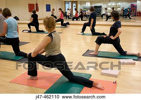 Stock Image - group of people in a pilates class, kneeling up stretching. Fotosearch
