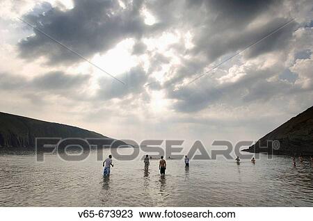 Group of young men and women standing and swimming in the sea at Mwnt Bay west of Cardigan town Wales UK. The bay and surrounding cliffs are owned by the National Trust View Large Photo Image Stock Image - Group of young men and women standing and swimming in the sea at Mwnt Bay west of Cardigan town Wales UK. The bay and surrounding cliffs are owned by the National Trust. Fotosearch