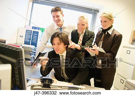 Group of young people, in an office all looking at the computer, smiling and pointing View Large Photo Image Stock Image - Group of young people, in an office all looking at the computer, smiling and pointing. Fotosearch