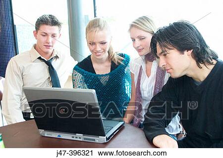 Group of young people, sitting at a table in a cafe, looking at a laptop View Large Photo Image Stock Image - Group of young people, sitting at a table in a cafe, looking at a laptop. Fotosearch