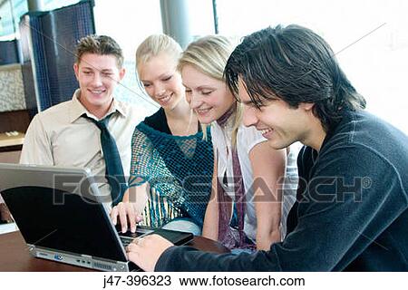 Group of young people, sitting at a table in a cafe, looking at a laptop, smiling View Large Photo Image Stock Image - Group of young people, sitting at a table in a cafe, looking at a laptop, smiling. Fotosearch