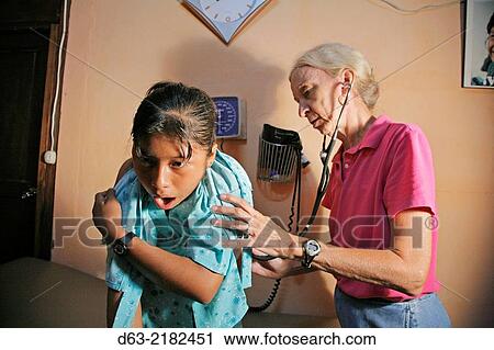 Stock Image - GUATEMALA. American missionary sister/doctor examining a pateint in Caterina.. Fotosearch