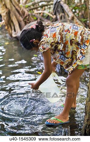Stock Photo - Guatemala, Rio Dulce, girl getting water from River. Fotosearch