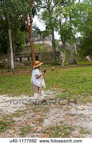 Stock Image - Guatemala, Tikal, Shaman walking with staff. Fotosearch
