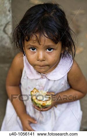 Stock Image - Guatemala, young girl eating fresh cacao. Fotosearch