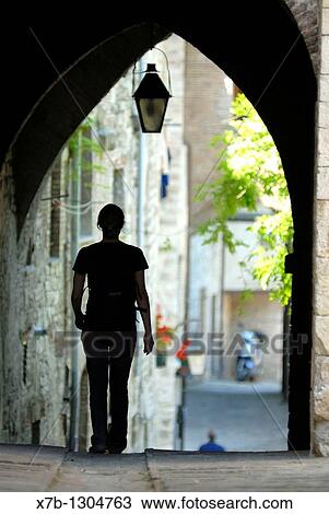 Gubbio Umbria Italy A woman walks under a covered arch in the backstreets View Large Photo Image Stock Image - Gubbio Umbria Italy A woman walks under a covered arch in the backstreets. Fotosearch