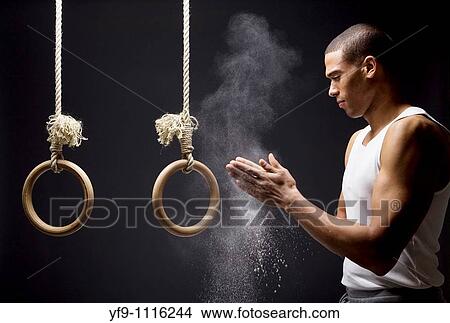 Gymnast man powdering hands on rings. View Large Photo Image Picture - Gymnast man powdering hands on rings.. Fotosearch